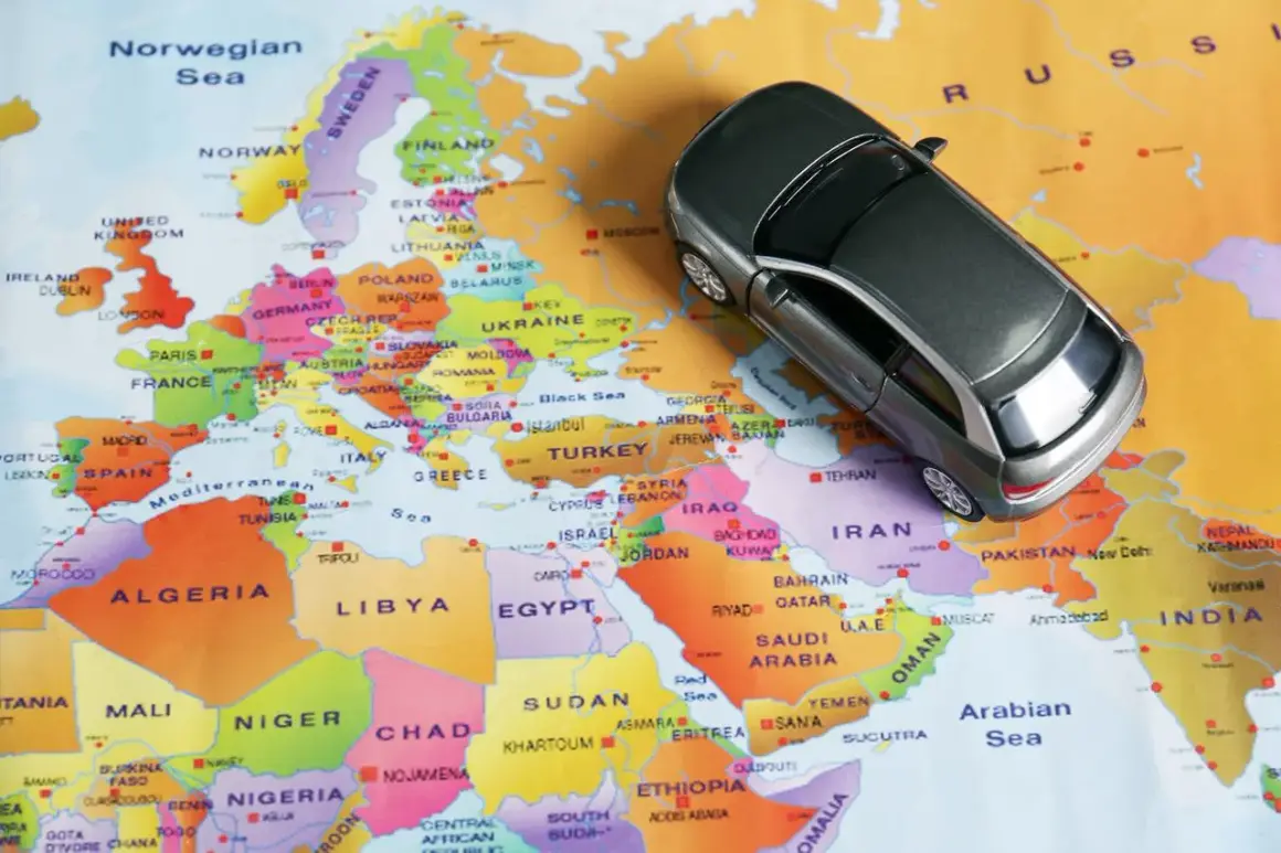 Une petite voiture grise sur une carte d'Europe. Conduite à gauche quel pays ? L'image suggère un voyage en Europe, où la conduite à gauche est la norme dans de nombreux pays.