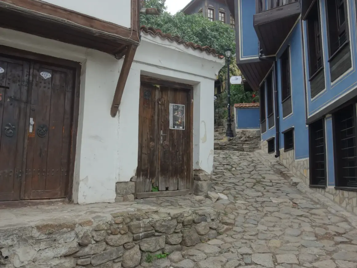 Kamienna uliczka w Plovdiv Bułgaria, z tradycyjnymi domami o białych i niebieskich fasadach.