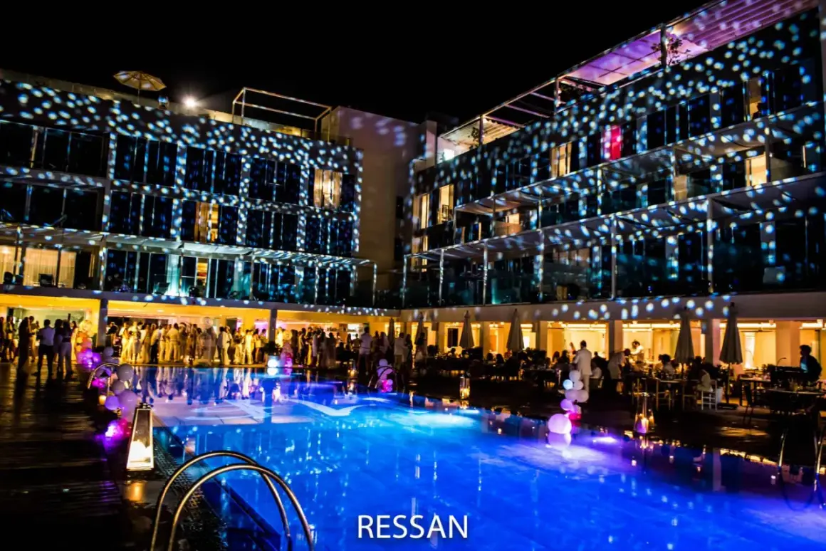 Una festa notturna con luci stroboscopiche su un edificio moderno e una piscina illuminata. Sembra un luogo ideale per locali scambisti a Ibiza.