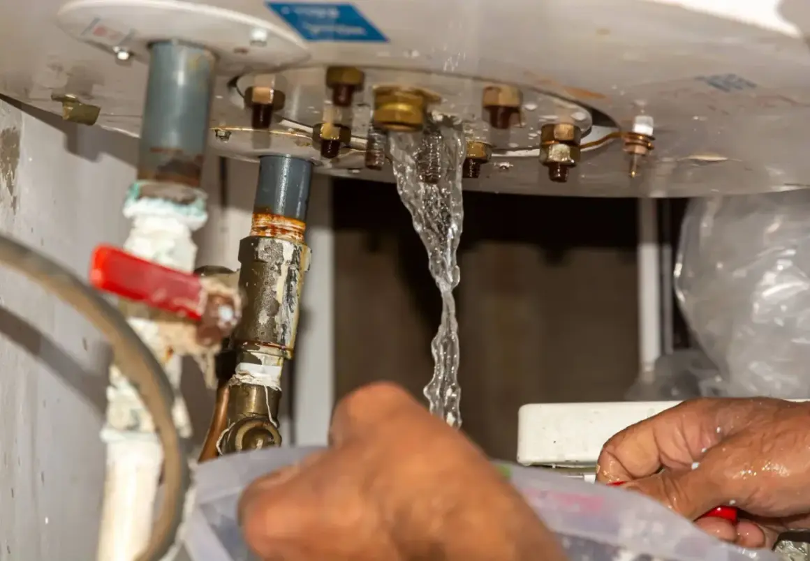 Fuite d'eau au niveau du ballon d'eau chaude, un plombier intervient pour l'entretien.