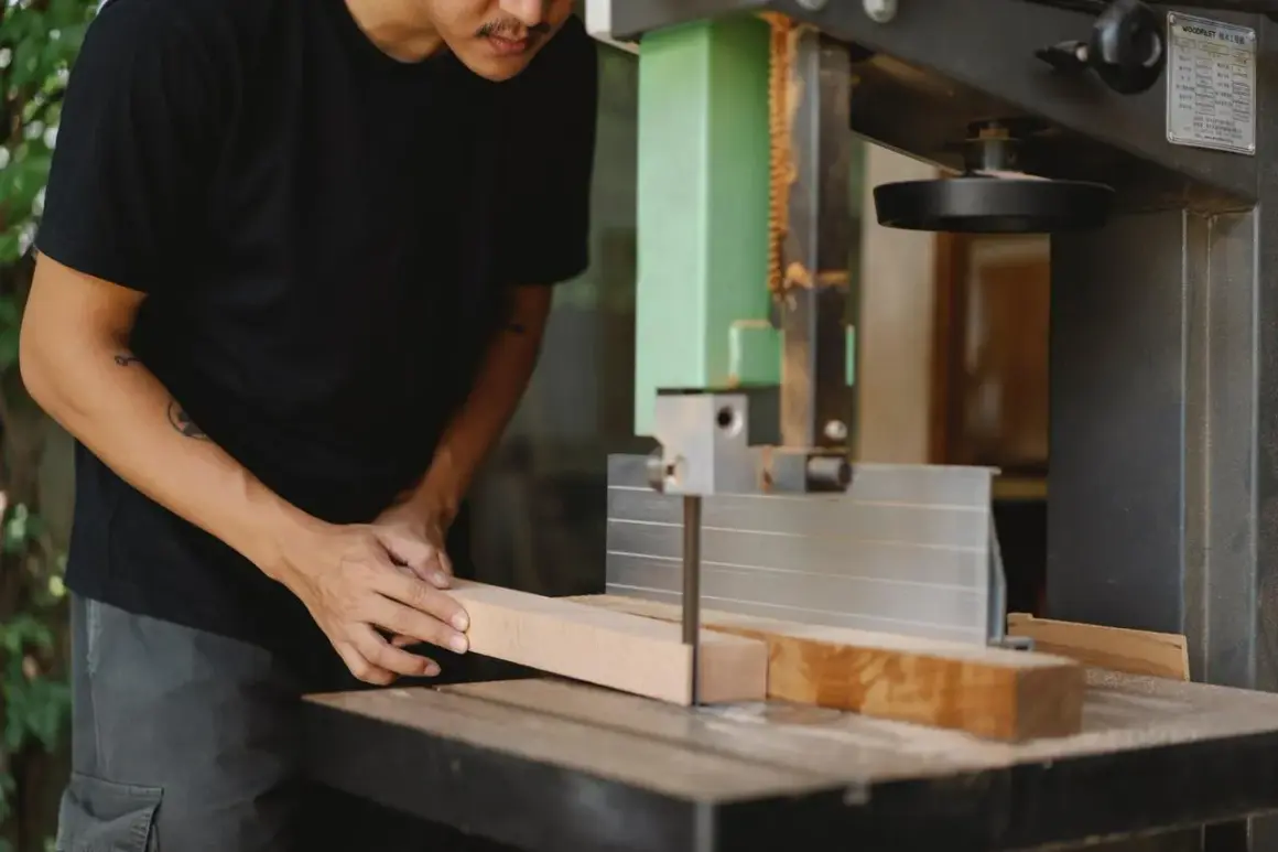 Un artisan utilise une scie stationnaire pour découper une pièce de bois.