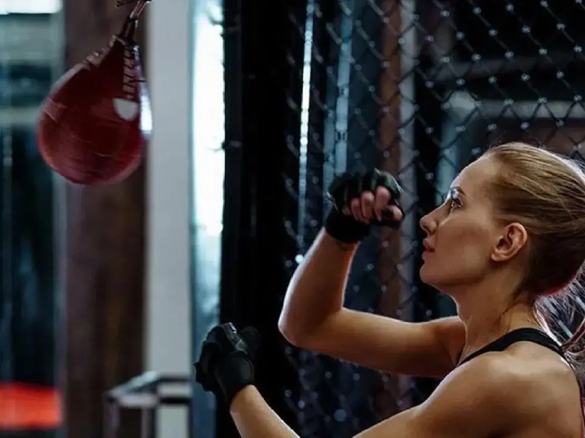 A woman trains with a speed bag, practicing her punches. This image shows a key element of how to make a speed bag workout effective.