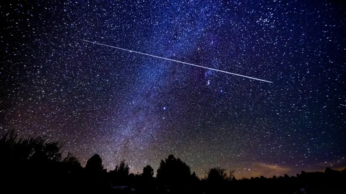 Una estrella fugaz cruza el cielo nocturno estrellado, ideal para ver las Perseidas en Madrid.