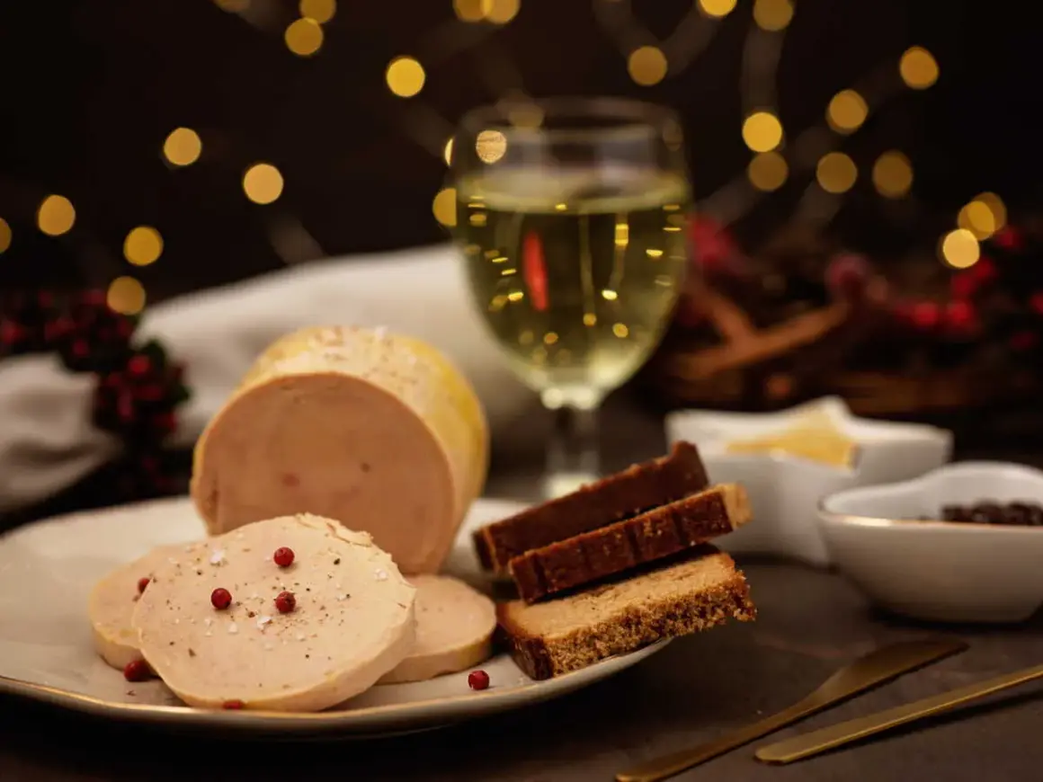 Un délicieux bloc de foie gras tranché, servi avec du pain d'épices et un verre de vin blanc, le tout dans une ambiance festive.