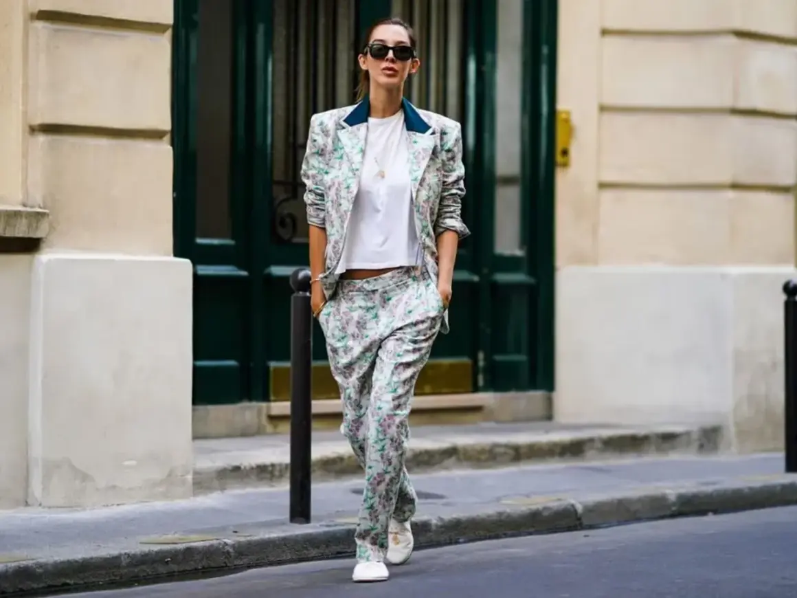 Donna con tailleur floreale e scarpe basse cammina per strada, con un'aria disinvolta e chic.