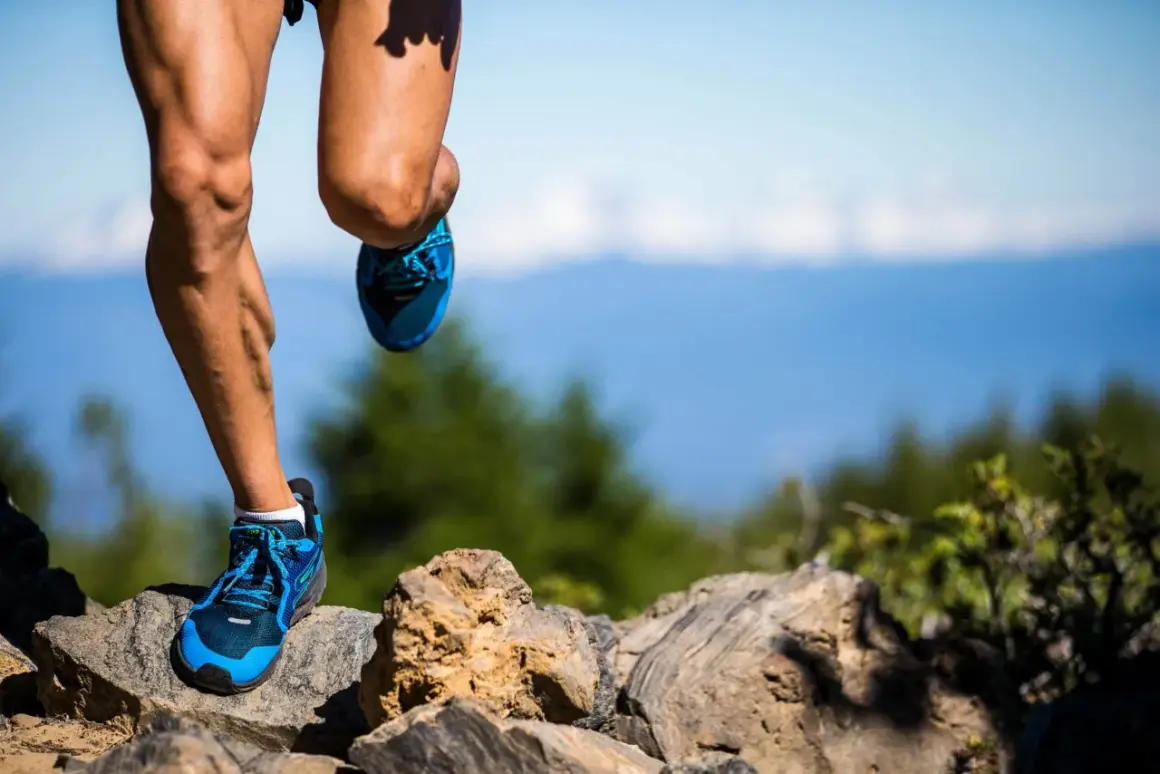 Nogi biegacza w niebieskich butach na kamienistym szlaku, przygotowującego się do ultramaratonu. Ile km? Tego nie wiemy, ale wysiłek jest widoczny.