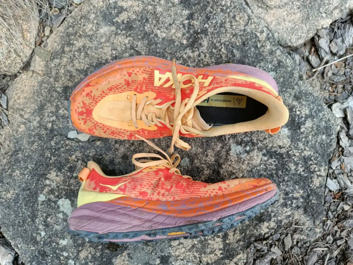 Kolorowe buty Hoka Speedgoat 6 na kamieniu. Hoka to firma znana z amortyzacji i komfortu.