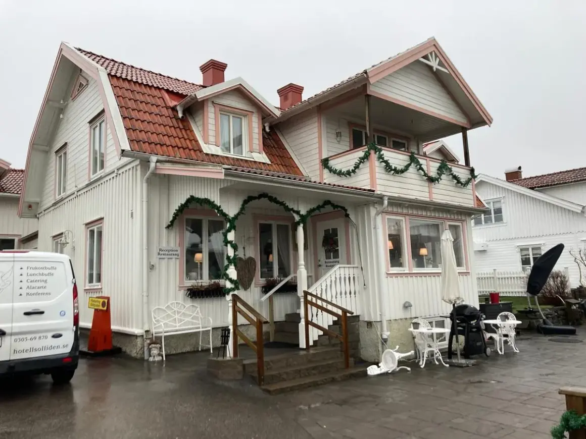 Vitt hus med rosa detaljer och juldekorationer. Skylt visar "Reception Restaurang". Kanske en titt på restaurang Solliden meny?