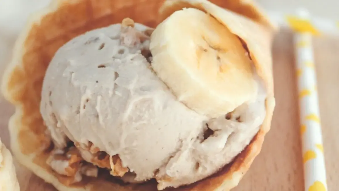 Delicioso helado de crema de cacahuete en un cono de gofre, coronado con rodajas de plátano.