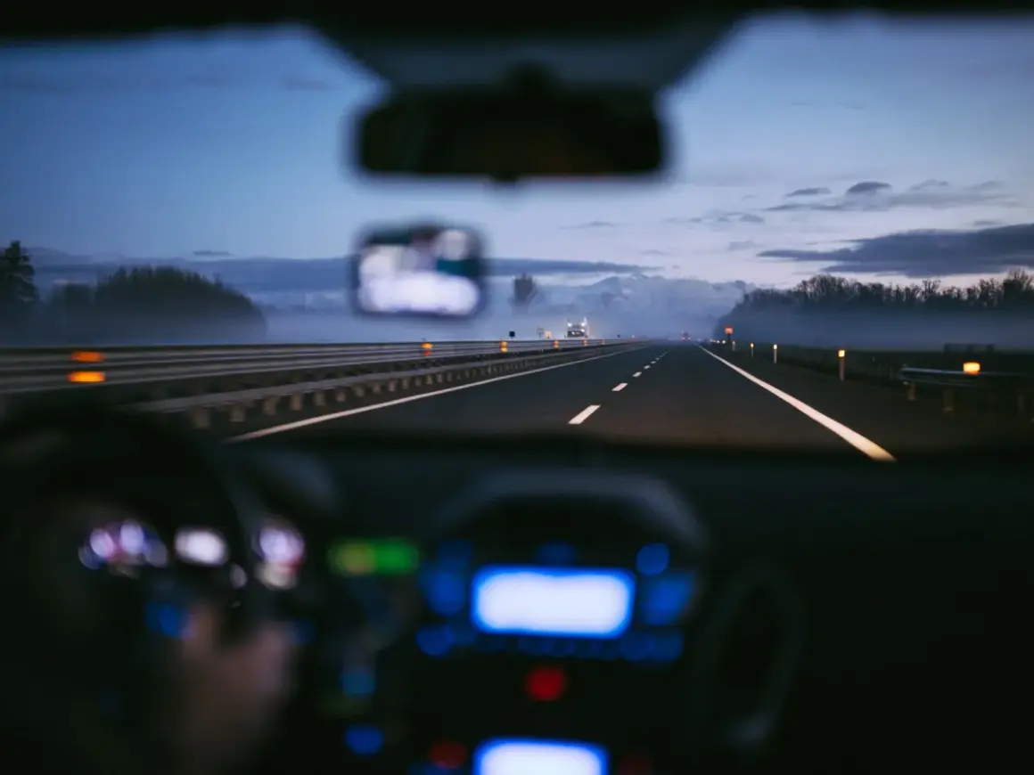 Conduite de nuit sur une autoroute italienne, respectant la limitation de vitesse. Brouillard léger, lumières des phares et du tableau de bord.