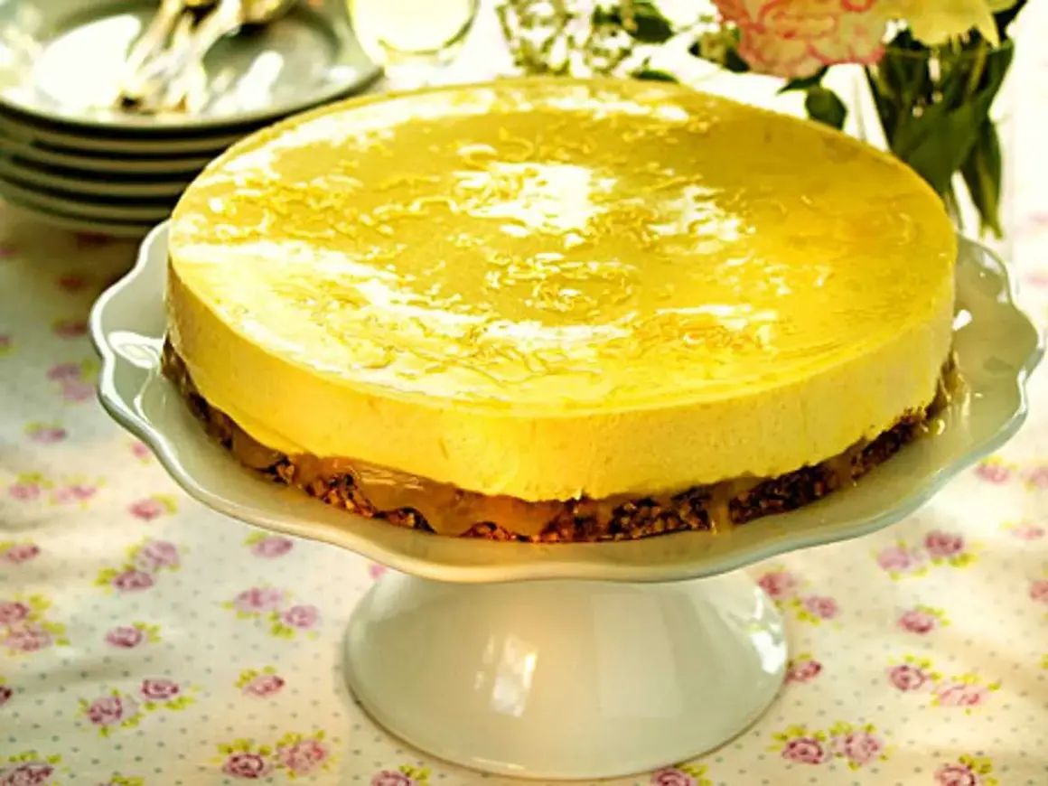 En härlig citronmousse till tårta, med en krispig botten och glansig topping, serveras på ett vackert tårtfat.