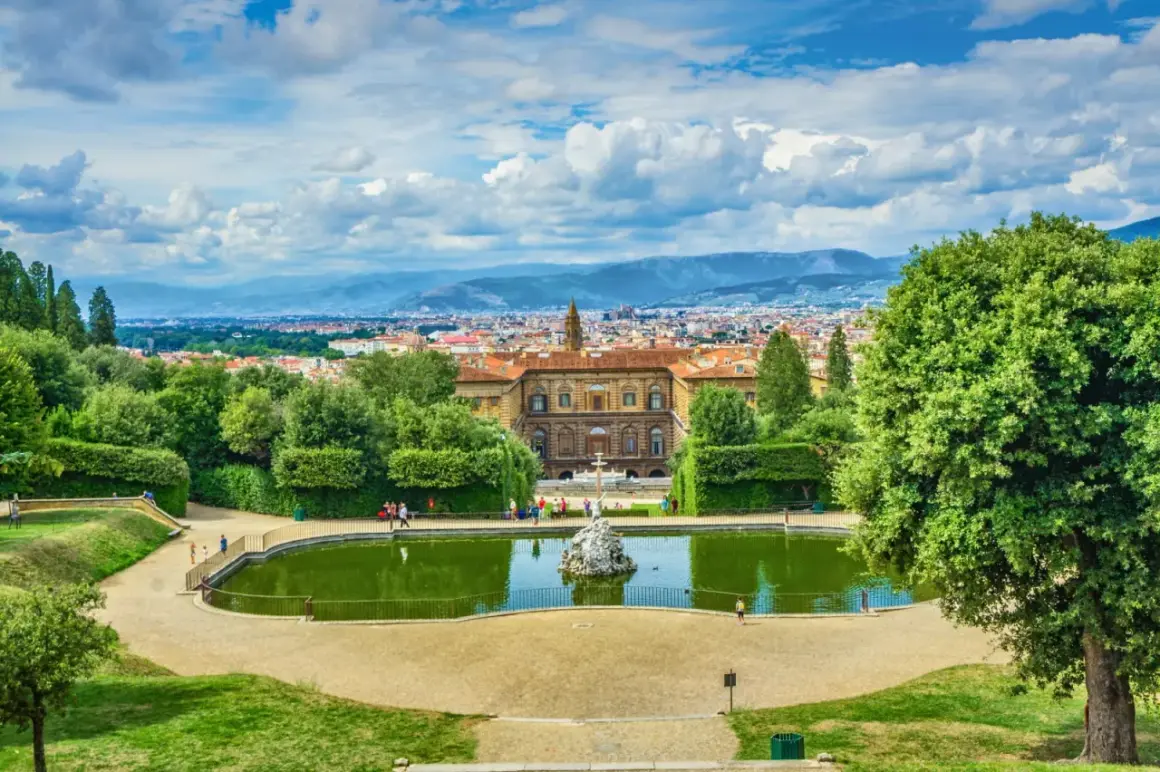 Vista panoramica dei Giardini di Boboli con stagno, palazzo e Firenze sullo sfondo.