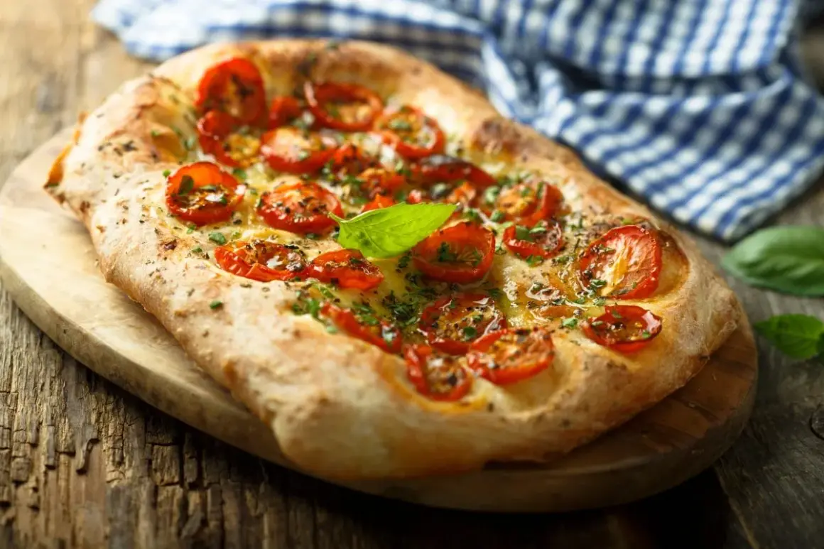 Pyszna focaccia z pomidorkami koktajlowymi i bazylią. Idealna jako przekąska, dodatek do sałatek lub jako samodzielne danie. Z czym jeść focaccię? Z tym, co lubisz!