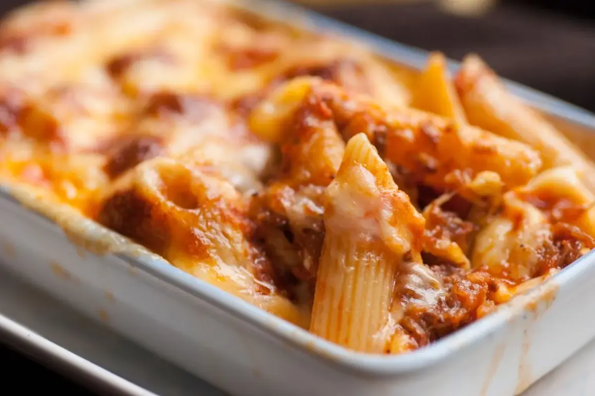 Un invitante piatto di pasta al forno, con penne ricoperte da un ricco sugo e formaggio fuso dorato.