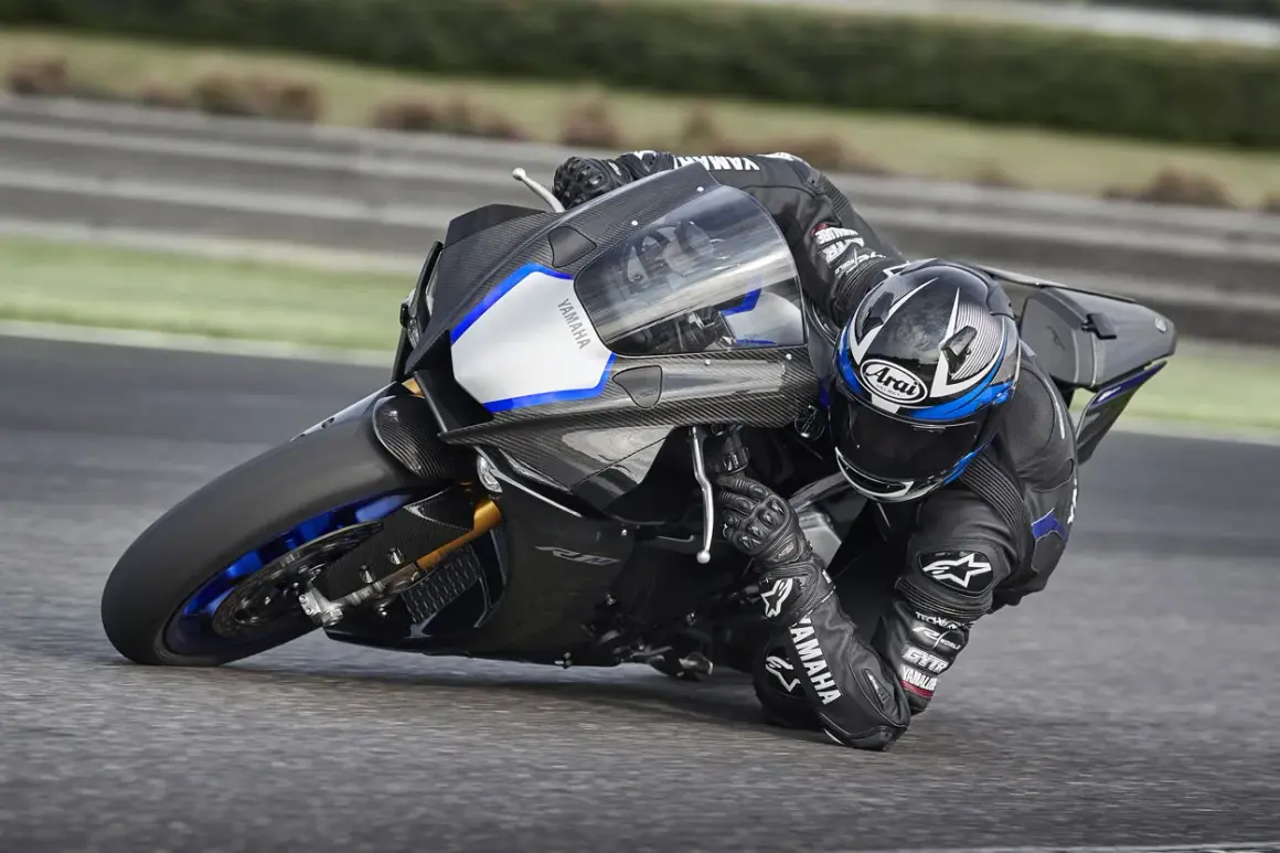 Piloto en Yamaha R1, la moto más potente, inclinado en una curva en circuito.