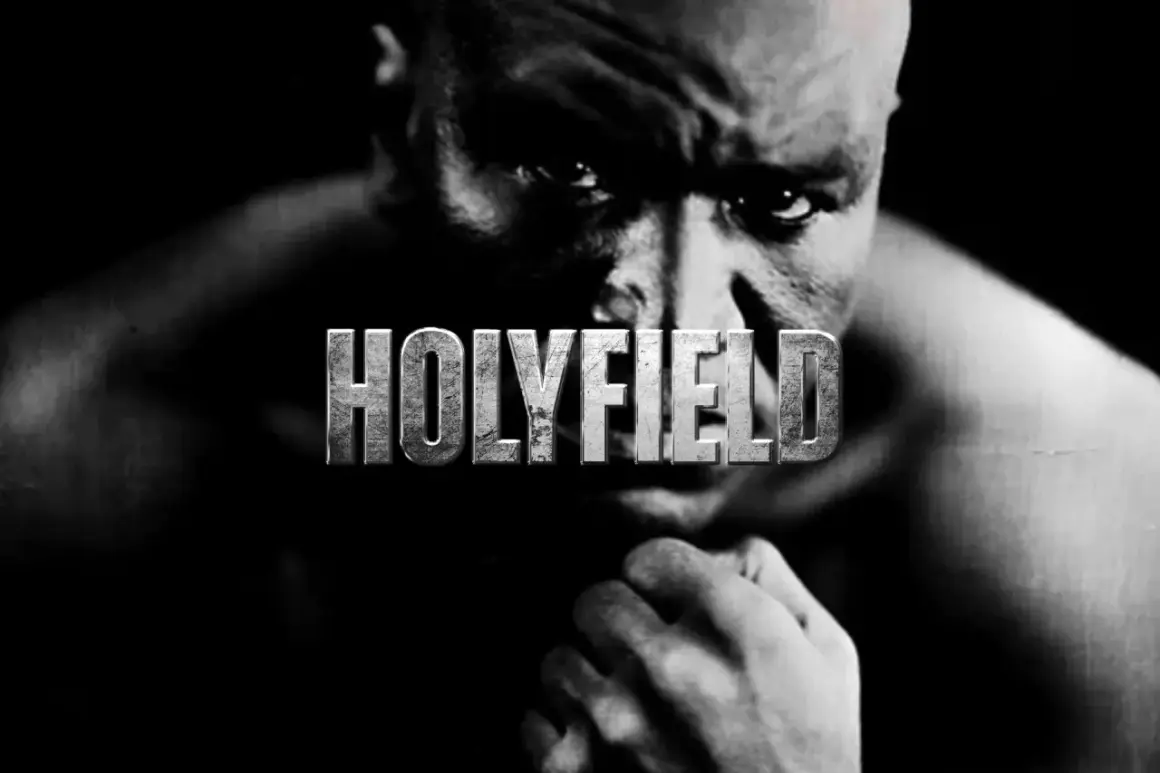 A close-up, black and white portrait of Evander Holyfield, the legendary boxer, with the word "HOLYFIELD" emblazoned across his face.