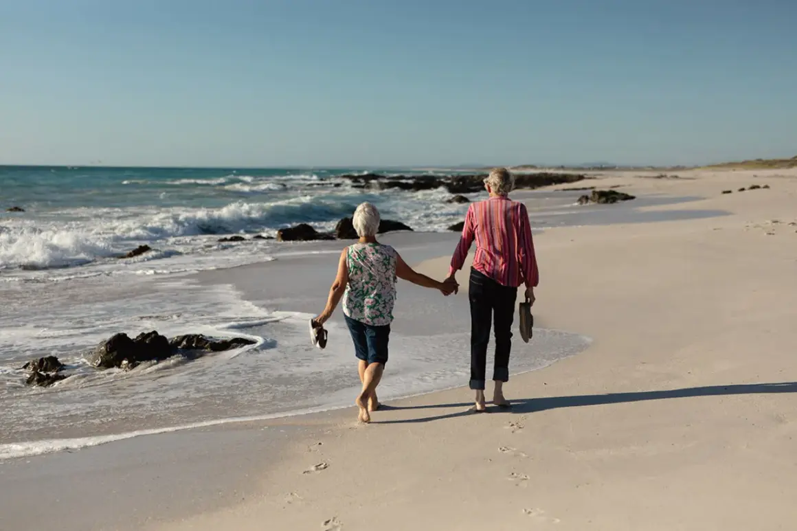 Para świętuje 70 rocznicę ślubu, spacerując boso po plaży, trzymając się za ręce.