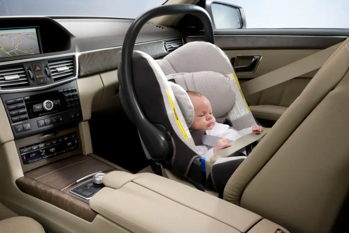 Un bébé dort paisiblement dans un siège auto, prêt pour le voyage. La **taille pour monter devant en voiture** est parfaite pour ce siège.