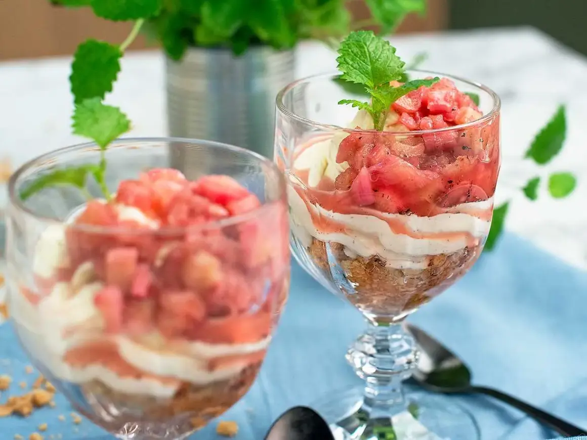 Två glas med en härlig dessert av rabarber i glas, varvad med krämig vanilj och smulad kaka. En frisk och somrig smakupplevelse.