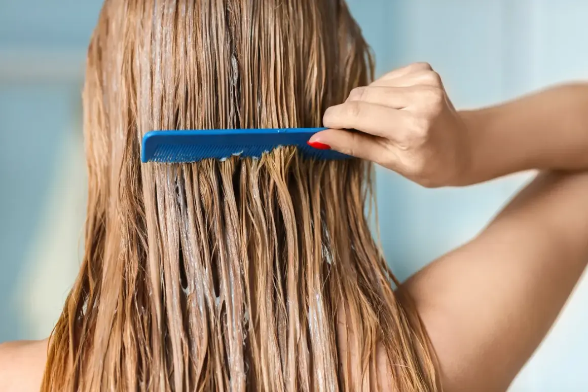 Une main peigne des cheveux blonds humides, recouverts d'un masque argile avant coloration végétale.