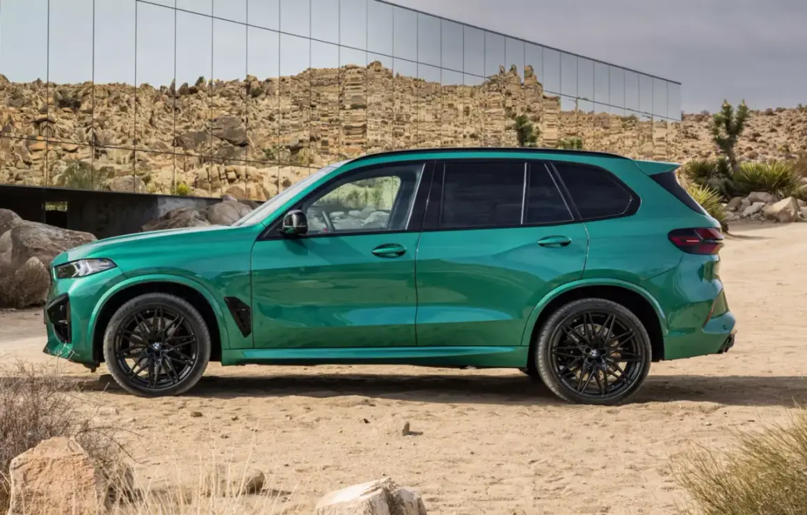 Zielony SUV, idealne ekonomiczne auto na długie trasy, zaparkowany na pustynnym tle z nowoczesnym budynkiem w tle.