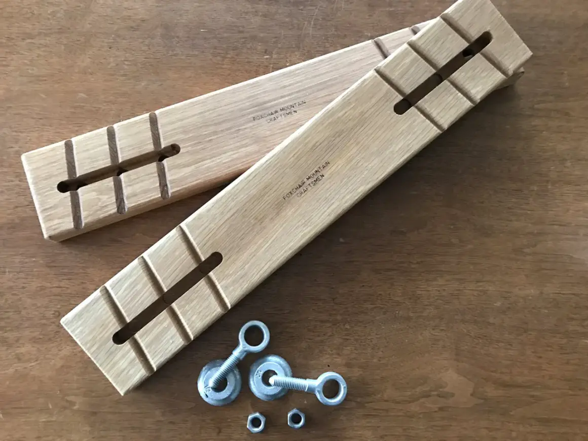 Two wooden batter boards with slots and notches, alongside eye bolts and nuts, ready for a construction project.