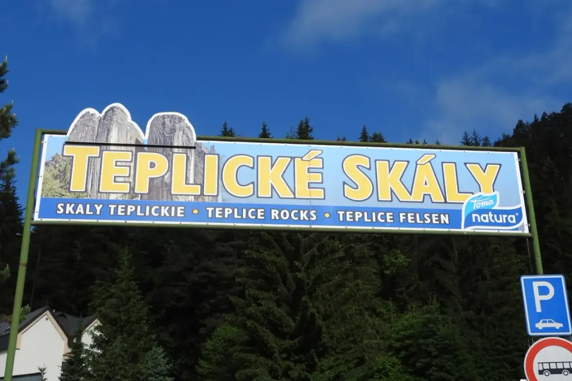 Tablica informacyjna zapraszająca na trasę po skalach w Teplicach. Widoczne skalne formacje i napis "TEPLICKÉ SKÁLY".