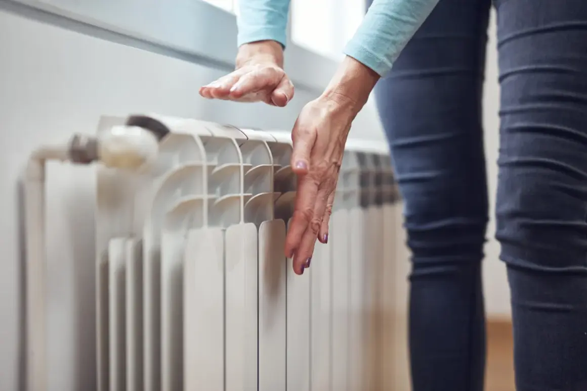 Dłonie sprawdzają temperaturę grzejnika, zastanawiając się, dlaczego grzejnik jest zimny na dole.