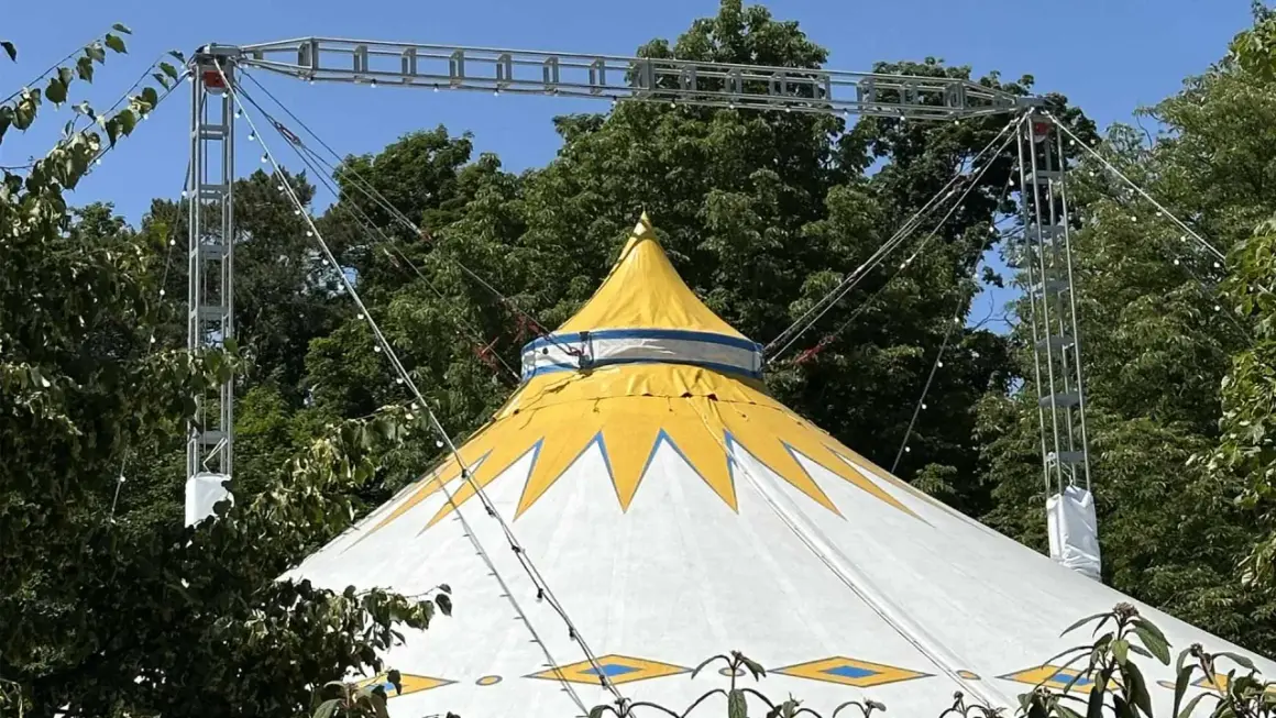 Gelbes und weißes Zirkuszelt mit Sternenmuster, das auf ein Sommerfest im Kulturzelt Kassel hindeutet.
