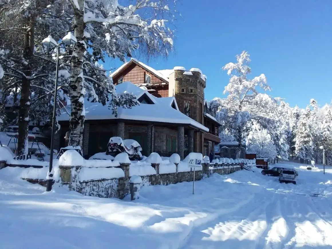 Un hermoso paisaje de Albania en invierno, con una casa cubierta de nieve y árboles nevados bajo un cielo azul brillante.