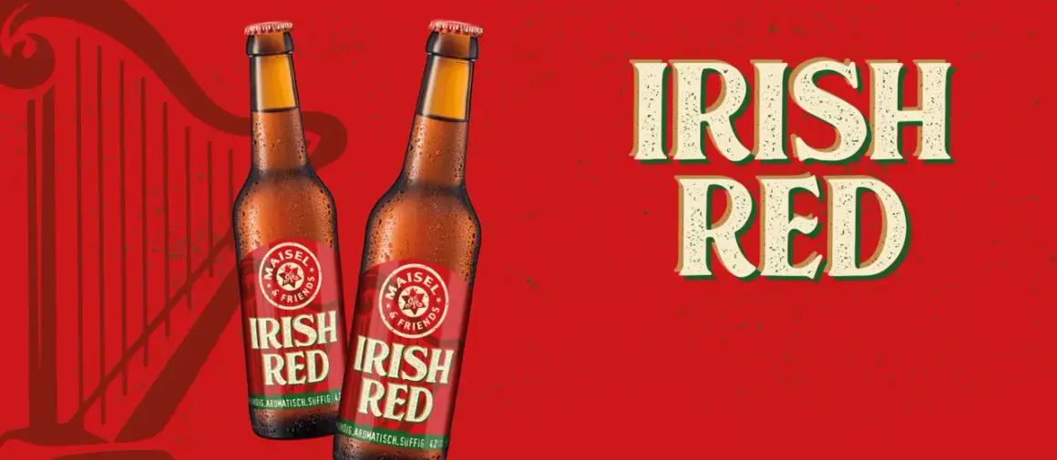 Zwei Flaschen "Irish Red" Bier vor rotem Hintergrund mit Harfenmotiv. Was ist Rotbier? Dieses Irish Red Ale ist vollmundig, aromatisch und süffig.
