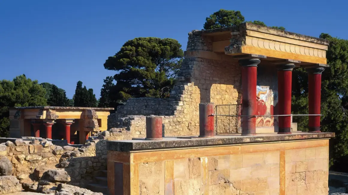 Ruinas del palacio de Cnosos con sus icónicas columnas rojas y un fresco de toro.