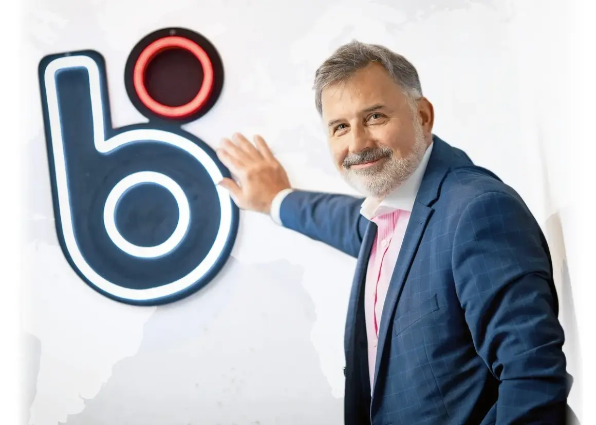 Mężczyzna w garniturze opiera się o logo, które może sugerować, kto wymyślił BLIK.