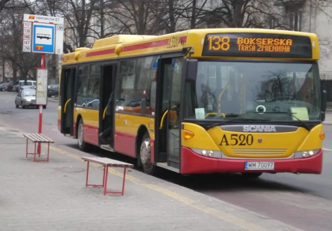 Żółto-czerwony autobus 138 warszawa z otwartymi drzwiami na przystanku.