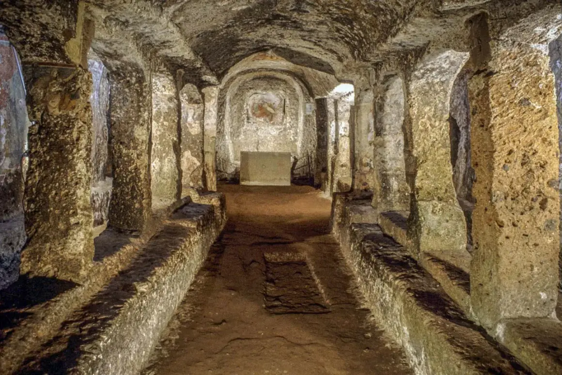 Corridoio sotterraneo con sedute in pietra e affreschi sbiaditi, parte dell'antico borgo di Sutri.