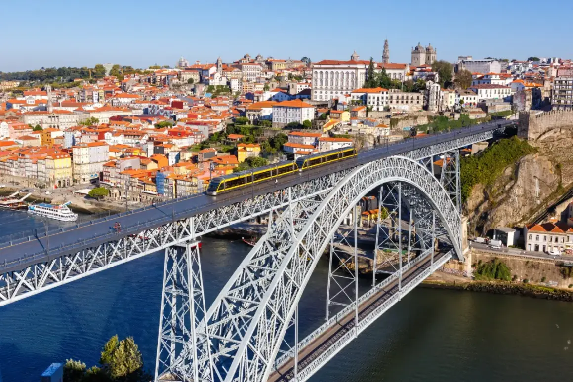 Most zwodzony w Porto z żółtym tramwajem, widok na miasto i rzekę. Szukasz informacji o wino porto cena?