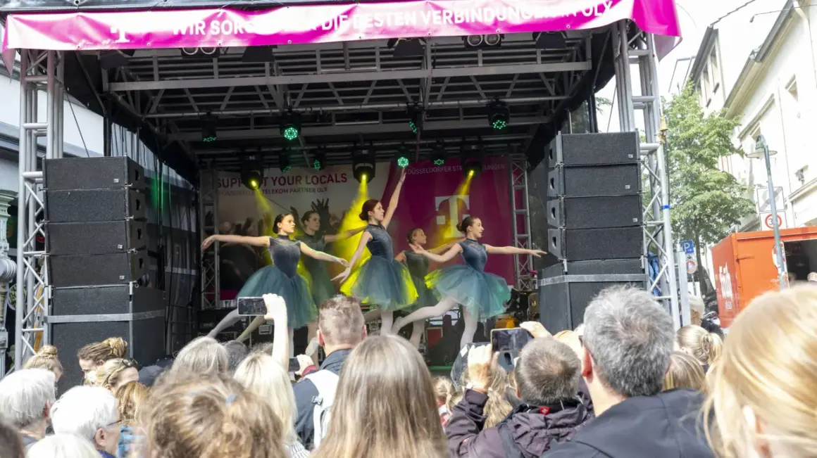 Ballettgruppe auf einer Bühne bei Veranstaltungen im Bergischen Land. Ein Publikum filmt die Darbietung.