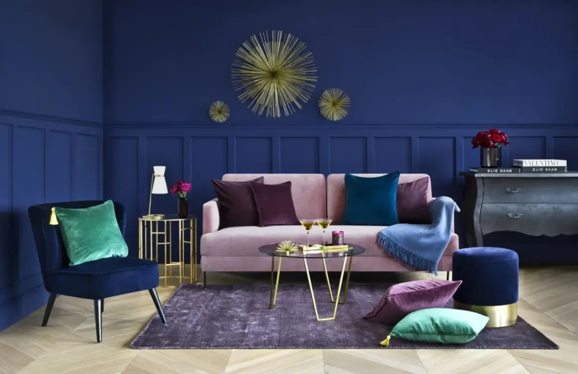 Elegancki salon z granatową ścianą, różową kanapą i złotymi dodatkami. Inspiracje dla odważnych.