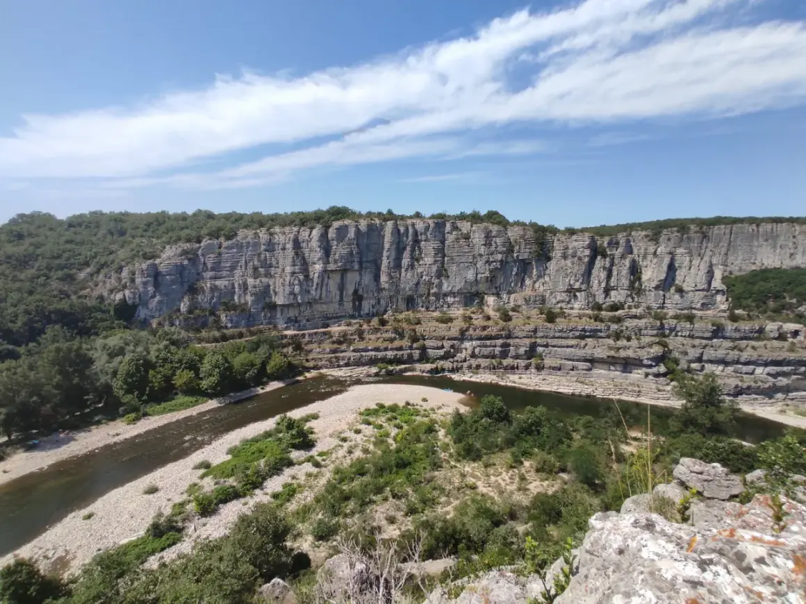 Un cirque de gens, des kayakistes profitent de la rivière au pied d'une falaise imposante.