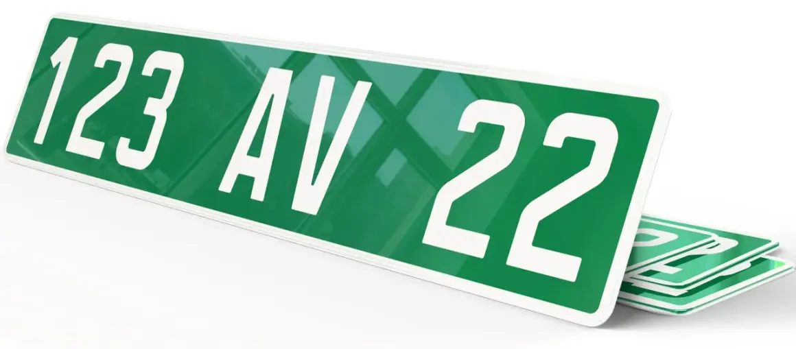 Plaque verte voiture avec "123 AV 22" en blanc. D'autres plaques similaires sont empilées en dessous.