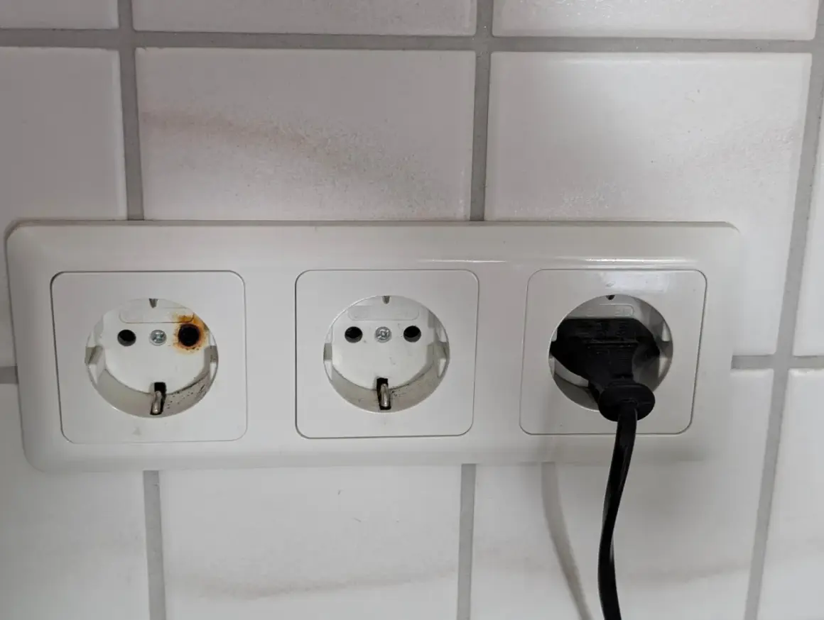 Eine Steckdose ist durchgebrannt, mit deutlichen Brandspuren im linken Anschluss. Ein Stecker ist im rechten Anschluss.
