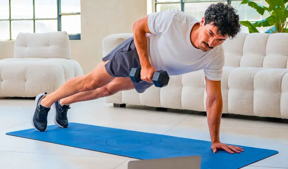Uomo in posizione di plank con manubrio, esercizio per come migliorare la postura. Allenamento a casa.