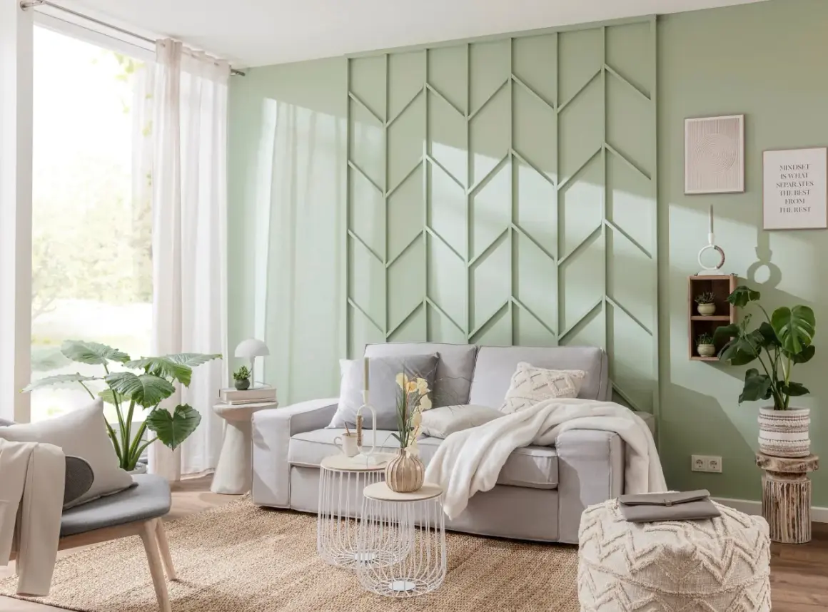 Eine stilvolle Wand hinter der Couch gestalten mit einem geometrischen Paneel in Mintgrün. Gemütliche Atmosphäre mit hellgrauem Sofa, Kissen und Decke.