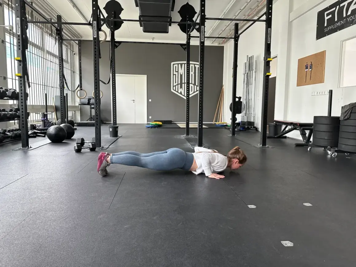 Frau macht Liegestütze im Fitnessstudio, ein Teil ihres plyometrischen Trainings.