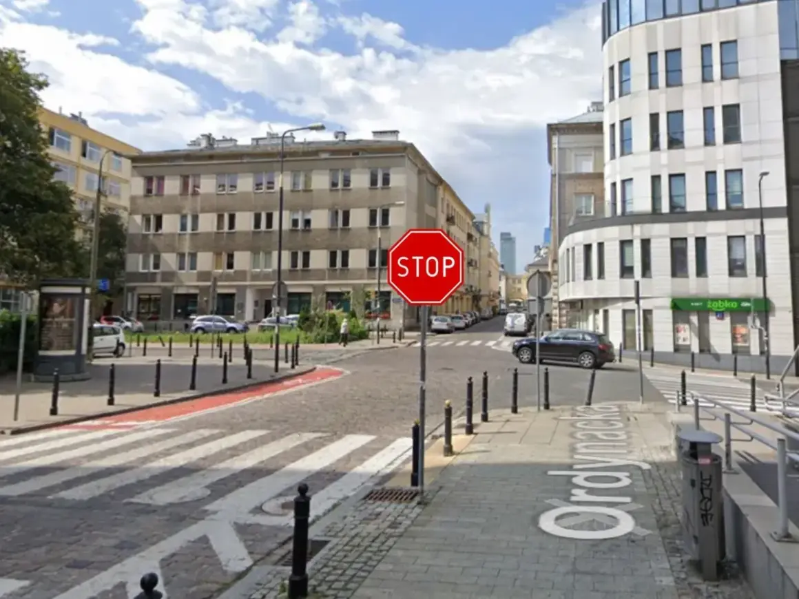 Widoczny znak stop na skrzyżowaniu ulic. Po prawej stronie budynek z napisem "Żabka".