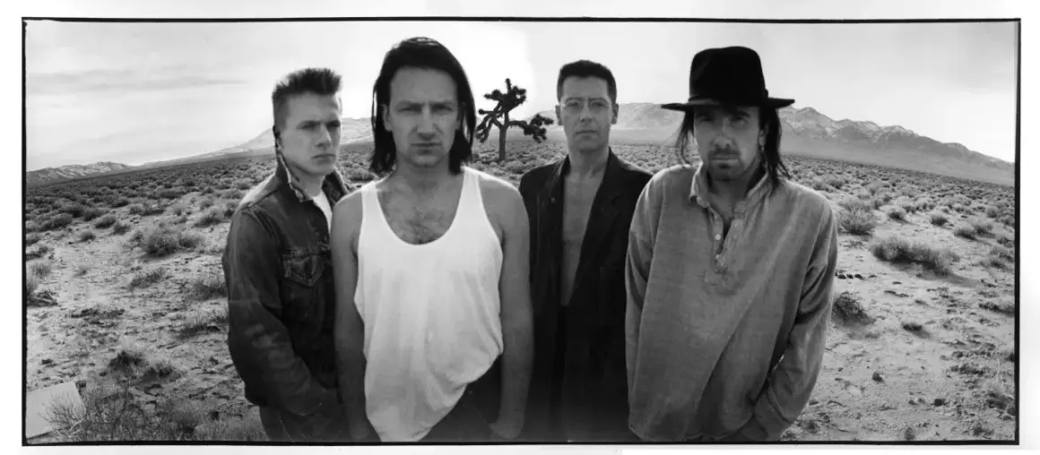 I membri degli U2 posano in un paesaggio desertico, con un Joshua Tree sullo sfondo.