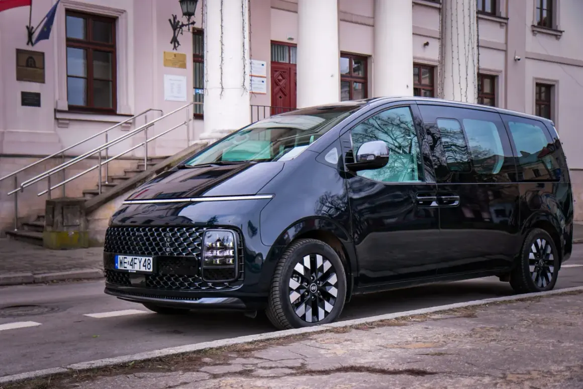 Czarny Hyundai Staria, nowoczesny van, zaparkowany przed budynkiem z kolumnami i schodami.