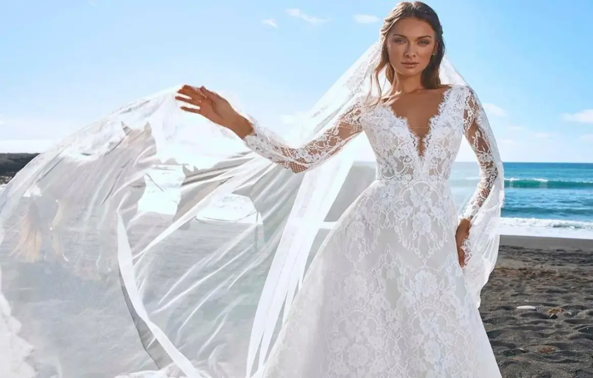 Une mariée sur une plage de sable noir, sa robe en dentelle et son voile flottant au vent, comme une cascade du voile de la mariée.