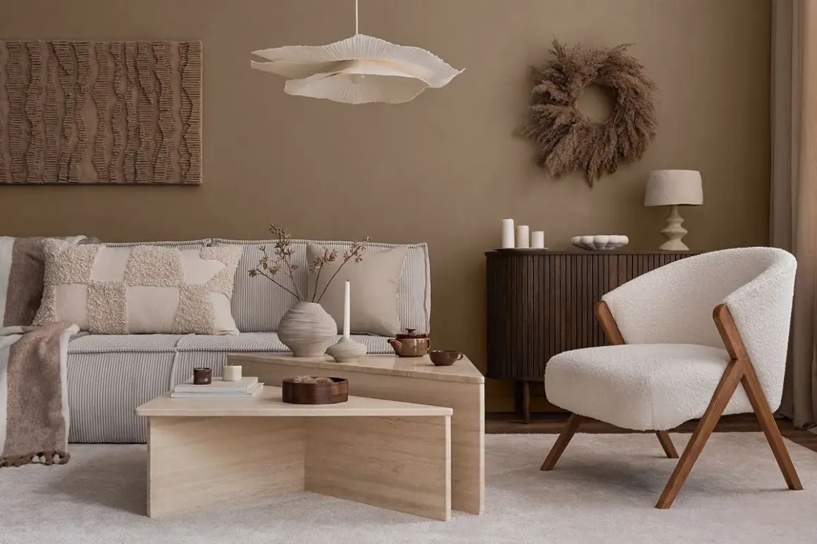 Przytulny salon w stylu naturalnym. Miękka sofa, puszysty fotel i kamienne stoliki tworzą oazę spokoju.