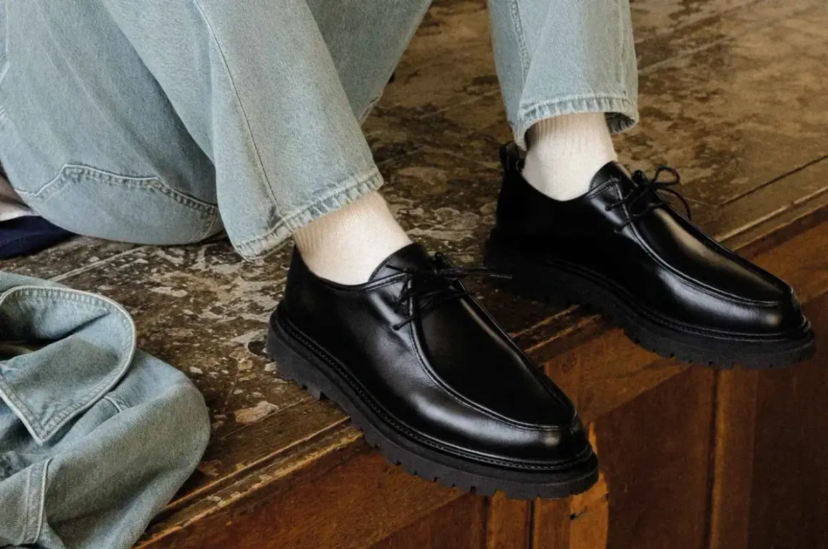 Paire de chaussures noires en cuir synthétique, lacées, avec une semelle épaisse. Parfaites avec un jean décontracté.